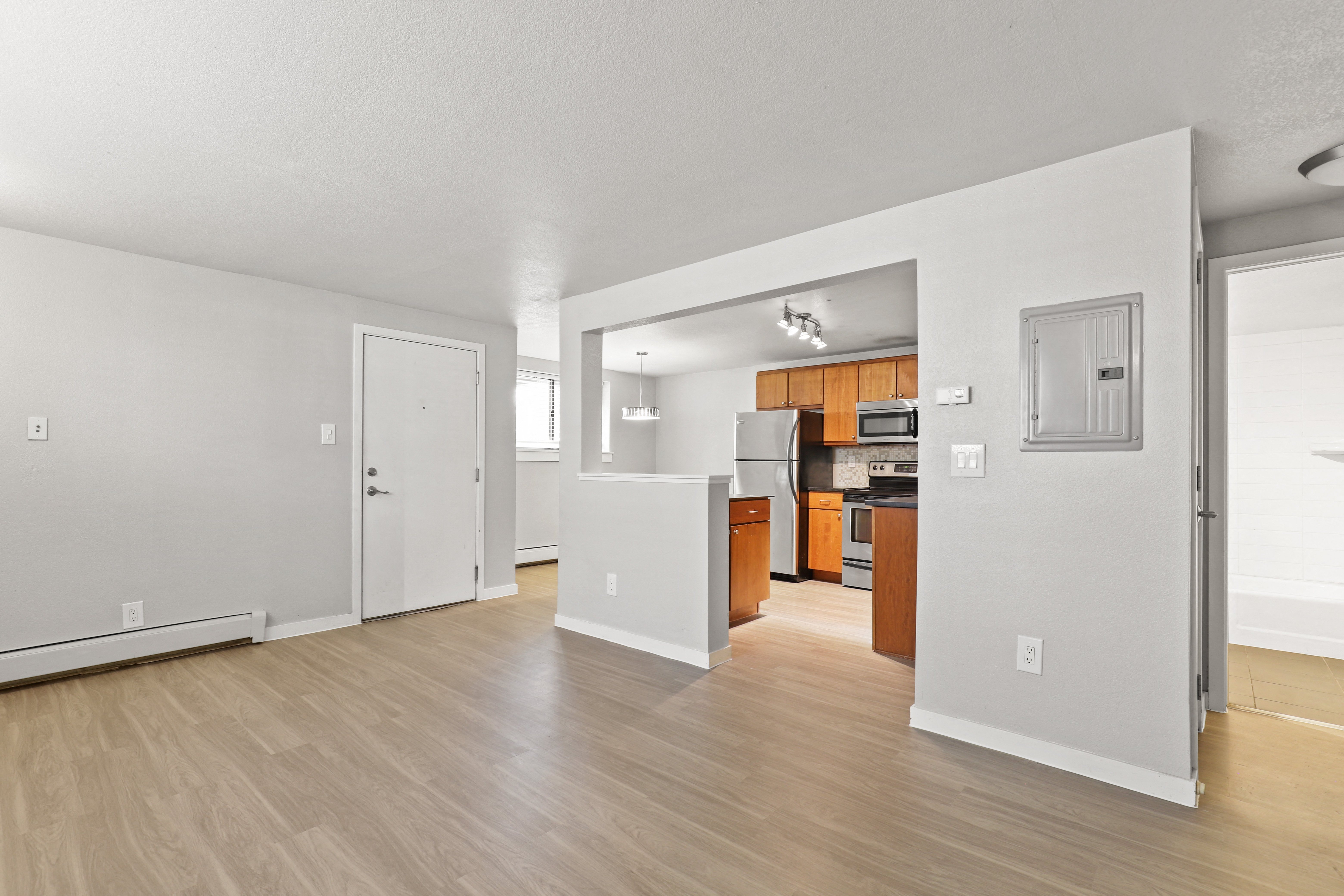 the living room and kitchen of an apartment with a hard wood floor